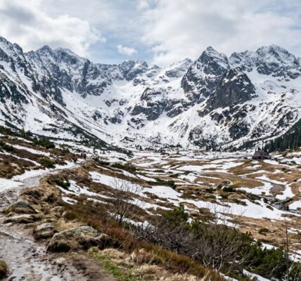 Górski krajobraz w Polsce z topniejącym śniegiem na szlaku i szczytach, pokazujący moment przejścia z zimy do wiosny